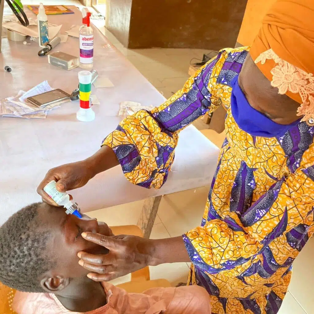 a doctor in ghana using the nanodropper to help a patient get their eyedrops