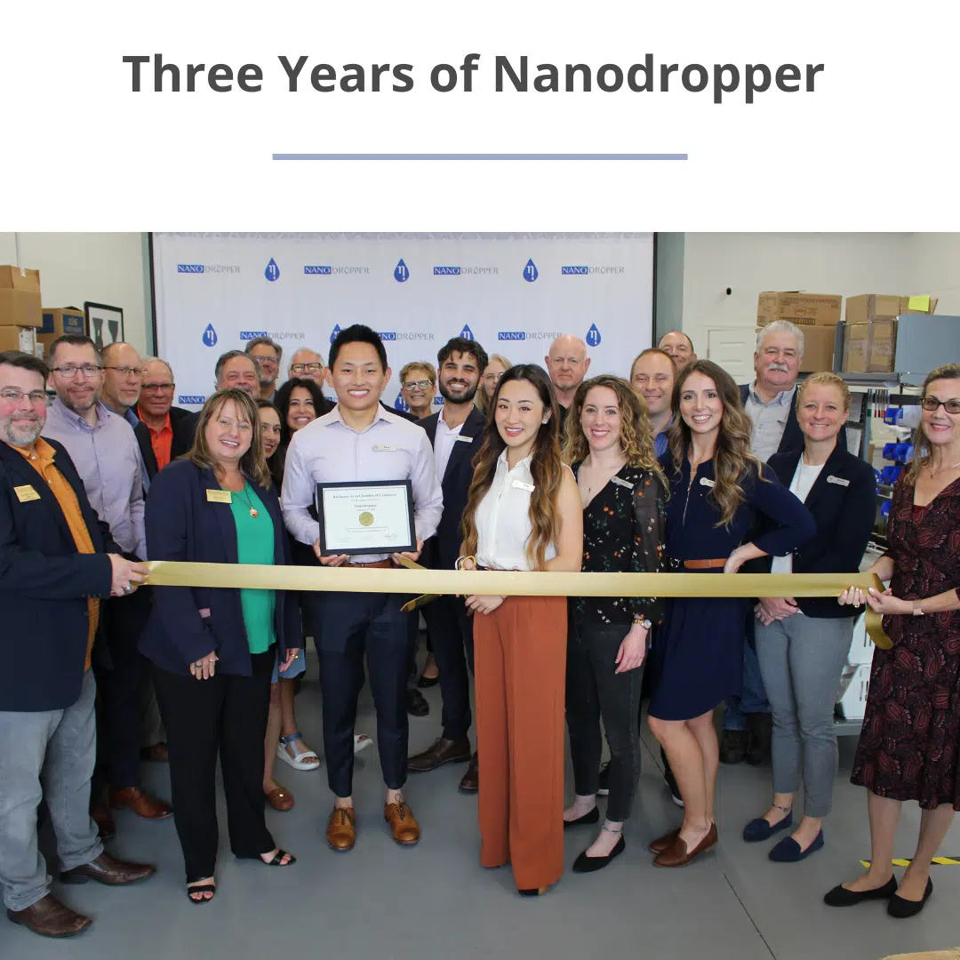 a group of people cutting a golden ribbon at the Nanodropper office, with the title of the blog up above