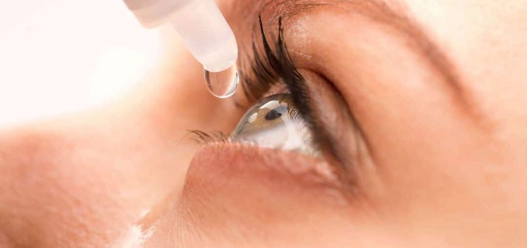 Eyedrop bottle hovering over eye with liquid spillage running down the cheek
